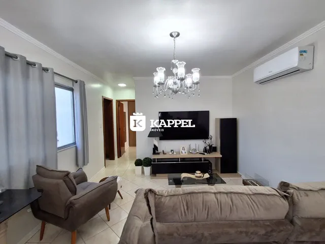 Sala de estar com sofá e televisão em um ambiente claro.
