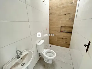 Banheiro com pia e vaso sanitário em um ambiente com revestimento de madeira.
