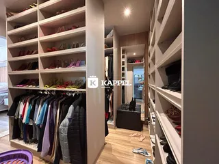 Quarto com estantes de roupas e sapatos em um ambiente interno.