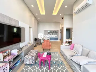 Sala de estar moderna com sofá, televisão e piso de madeira clara.