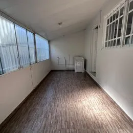 Vista interna de um corredor com piso de madeira e grandes janelas em um imóvel.