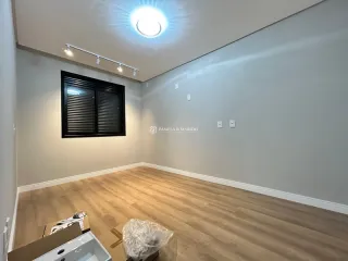 Ambiente interno com piso de madeira clara e teto com iluminação circular.