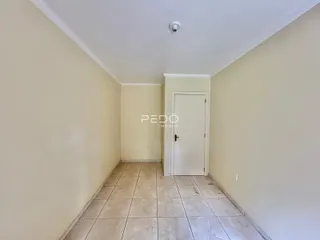 A foto mostra um corredor interno de uma residência com paredes claras e piso de cerâmica.