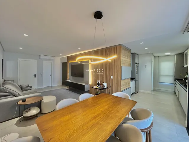 Sala de jantar e estar de uma residência moderna com mesa de madeira.