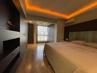 Quarto com cama grande e piso de madeira em um apartamento moderno.