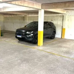Foto de uma garagem coberta com um veículo estacionado.