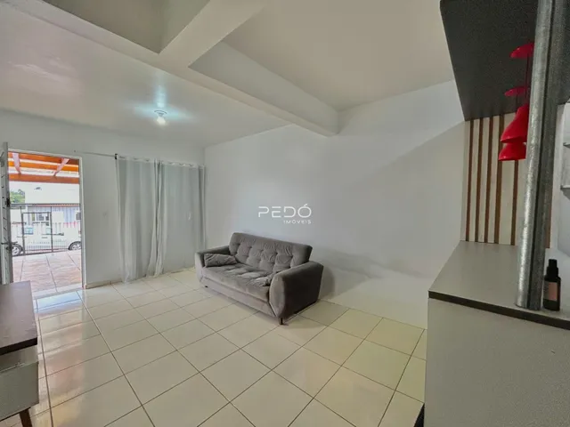 Sala de estar com piso de cerâmica clara e sofá cinza.