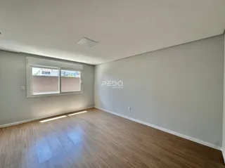 Uma sala de estar ampla com piso de madeira clara e paredes brancas.