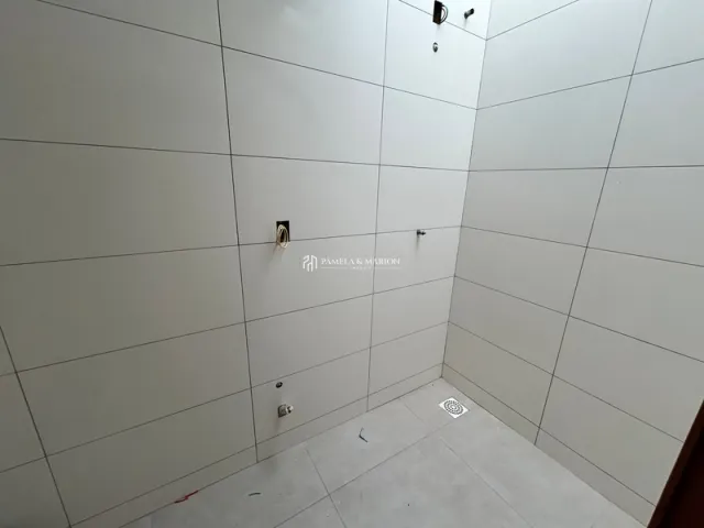 Hall de entrada com piso de cerâmica branca e paredes brancas.