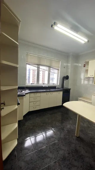 Cozinha com armários brancos e piso de cerâmica escura.