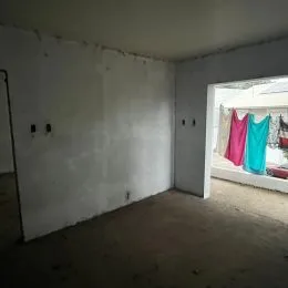 Foto de um cômodo interno com paredes brancas e piso cru.
