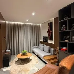 Sala de estar com cortinas e sofá em um imóvel.