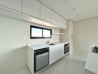 Cozinha moderna com armários brancos e piso claro.