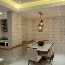 Parede texturizada com acabamento em ladrilhos brancos e teto claro em um ambiente interno.