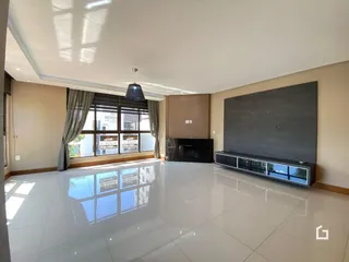 Sala de estar ampla com piso de porcelanato claro e parede de destaque moderna.