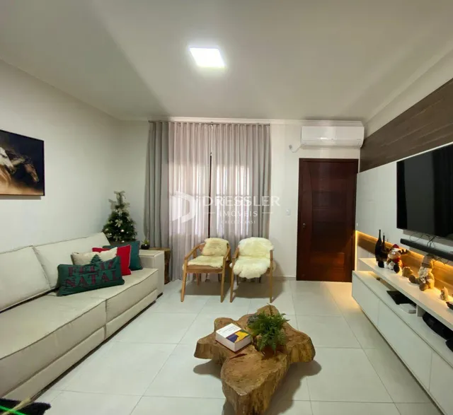 Sala de estar com sofá branco e cortinas claras em um imóvel no Brasil.