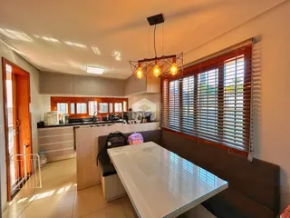 Sala de estar com cozinha integrada e grandes janelas com persianas.