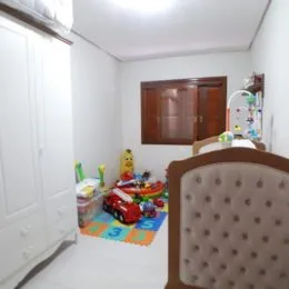 Quarto com armário de madeira e brinquedos espalhados no chão.