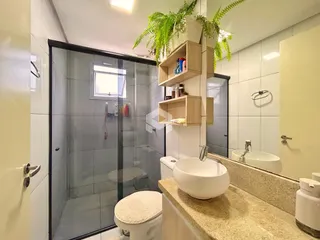 Foto de um banheiro com box de vidro e bancada de pedra.