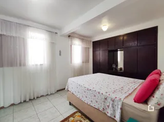 Quarto com cama e cortinas brancas.