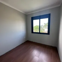 Vista parcial de um cômodo com piso de madeira e parede clara.