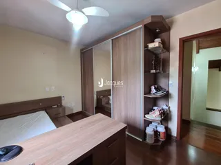 Quarto com cama e guarda-roupa de madeira em um imóvel no Brasil.