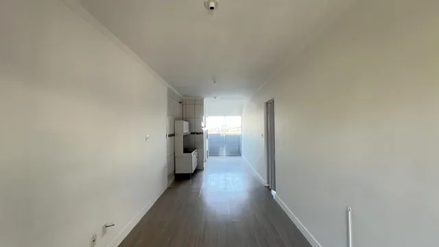 Corredor interno de uma residência com piso de madeira clara.