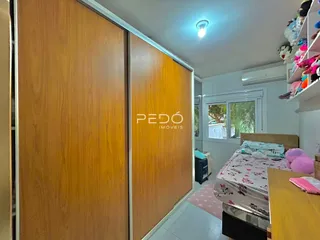 Quarto com guarda-roupas de madeira e cama visível.