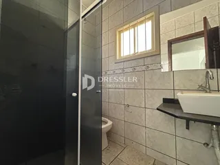 Foto de um banheiro com box de vidro e azulejos claros.