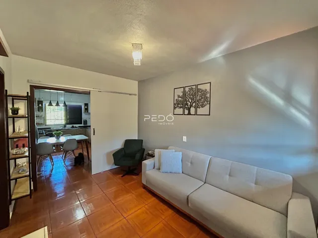 Sala de estar com piso de madeira e sofá claro.