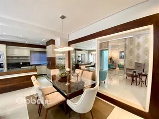 Uma sala de jantar moderna com mesa de vidro e cadeiras em um imóvel.