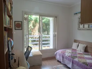 Quarto com janela de madeira e vista para a vegetação externa.