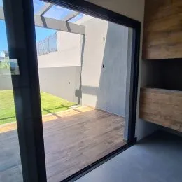 Vista de uma sala com piso de madeira e acesso a um jardim.