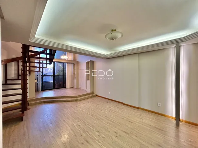 Interior de uma sala com piso de madeira e escadaria.