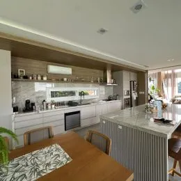 Cozinha moderna com armários brancos e bancada clara.