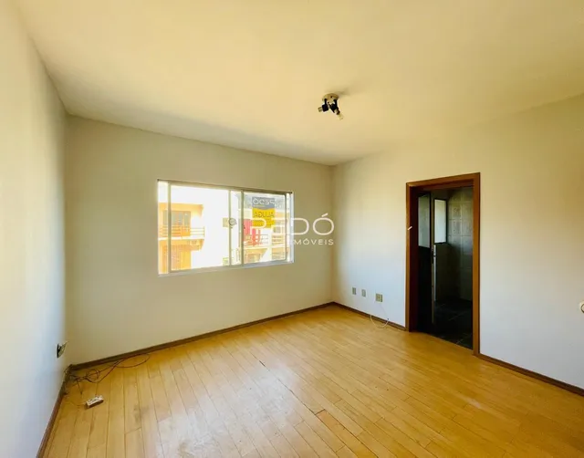 Ambiente interno de uma sala com piso de madeira clara e paredes brancas.