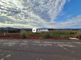 Vista externa de um terreno aberto com colinas ao fundo sob um céu nublado.