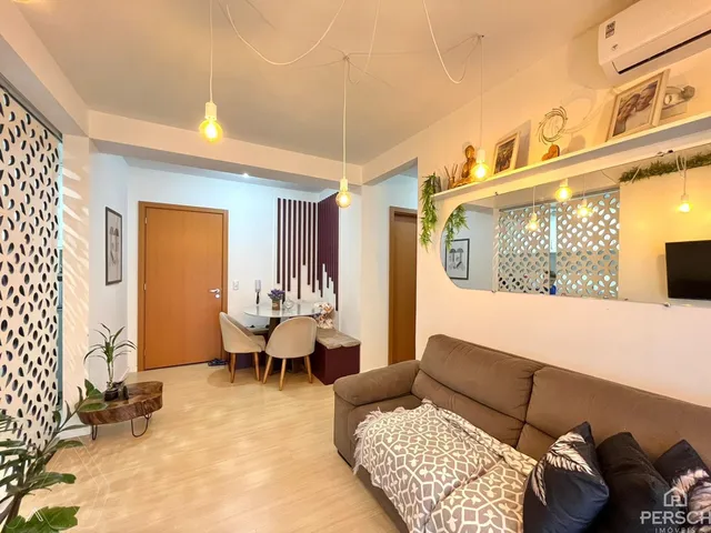 Sala de estar ampla com sofá e mesa de jantar em um apartamento em Lajeado.