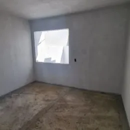 Foto interna de um cômodo com paredes brancas e piso de concreto.