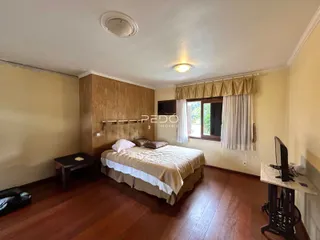 Quarto com piso de madeira e janela com cortinas.