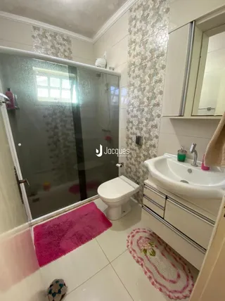 Foto de um banheiro com box de vidro e piso branco.