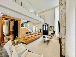 Sala de estar ampla com escadaria e parede de pedra no interior da residência.