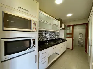 Cozinha com armários brancos e bancadas escuras.