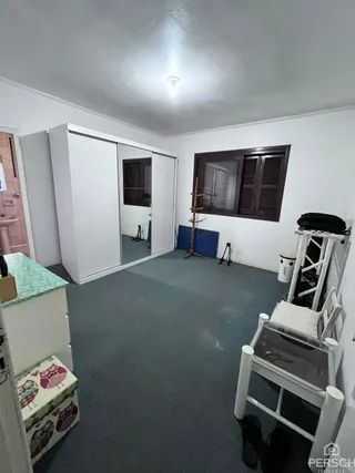 Ambiente interno com paredes brancas e piso cinza, mostrando um espaço com armários embutidos.