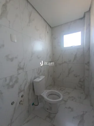 Banheiro com revestimento de azulejos brancos e piso claro.