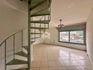 Interior de uma sala com escadaria e piso de cerâmica.