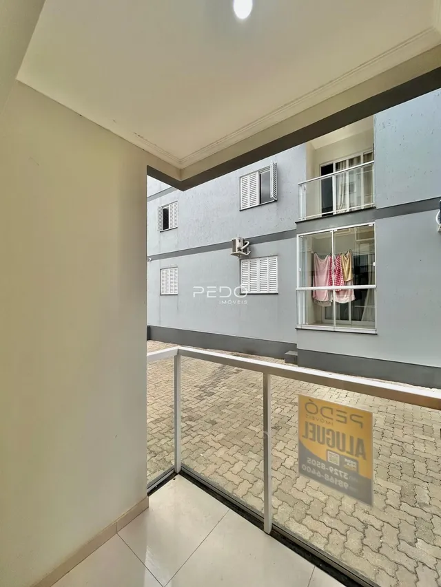 Vista de um corredor interno com acesso a uma área externa pavimentada.