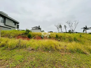 Vista externa de uma propriedade com terreno gramado e vegetação densa.