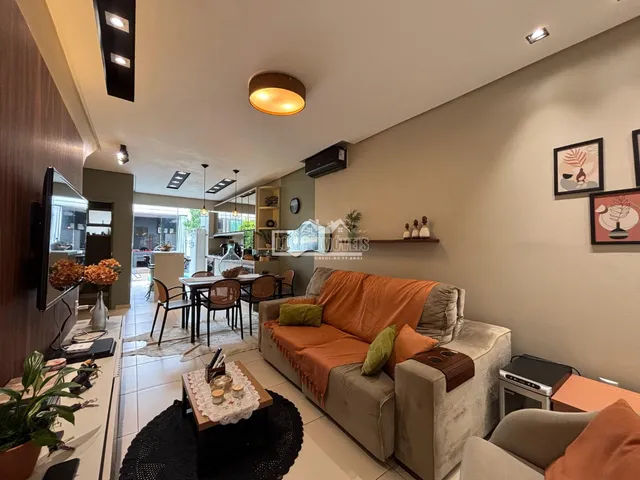 Sala de estar com sofá e área de jantar visível ao fundo.