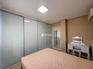 Quarto com cabeceira e armários em vidro na residência.